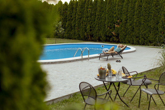 granite pool RMS Traders Pretty young woman lying on a deck char by the swimming pool in the house backyard